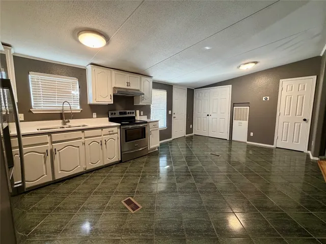 a large kitchen with stainless steel appliances a stove a sink a microwave and a refrigerator