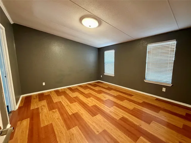 a view of a big room with wooden floor and windows
