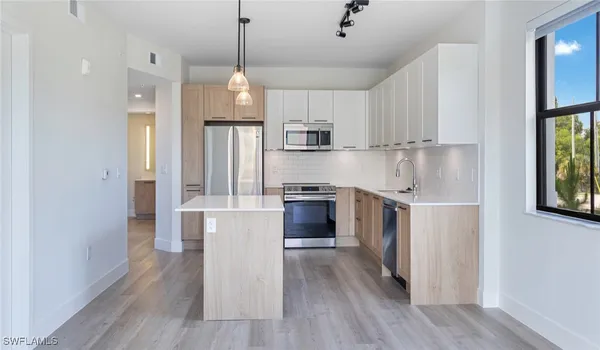 a kitchen with stainless steel appliances granite countertop a refrigerator a sink dishwasher a stove and white countertops with wooden floor