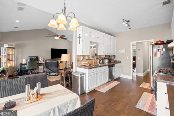 a open kitchen with stainless steel appliances kitchen island granite countertop a stove top oven a dining table and chairs with wooden floor
