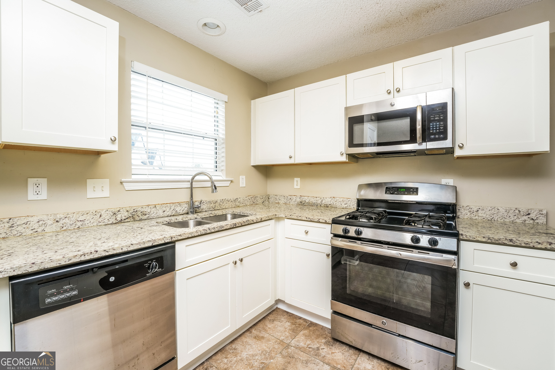 573 Ransom Way Stockbridge, GA 30281 - Photo 5 of 17 a kitchen with stainless steel appliances granite countertop a sink a stove a microwave and wooden cabinets
