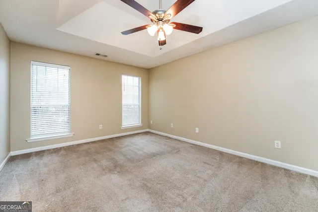 an empty room with windows and fan