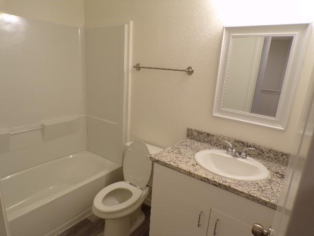 709 South 5th Street, Unit 1 Bonham, TX 75418 - Photo 26 of 32 a bathroom with a granite countertop toilet a sink and bathtub