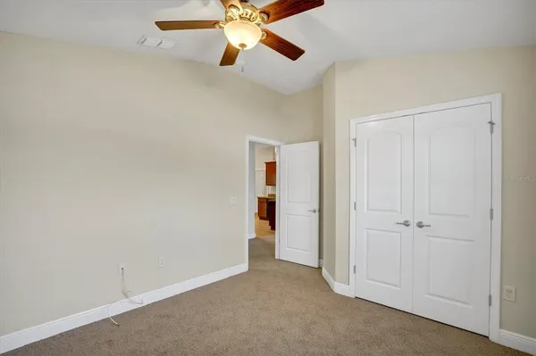an empty room with closet and a chandelier fan