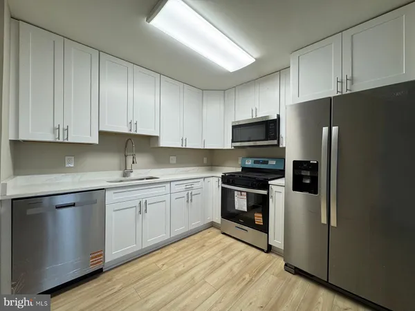 a kitchen with stainless steel appliances granite countertop a stove top oven a refrigerator and white cabinets