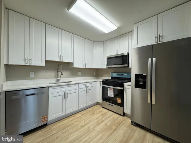 a kitchen with stainless steel appliances granite countertop a stove top oven a refrigerator and white cabinets