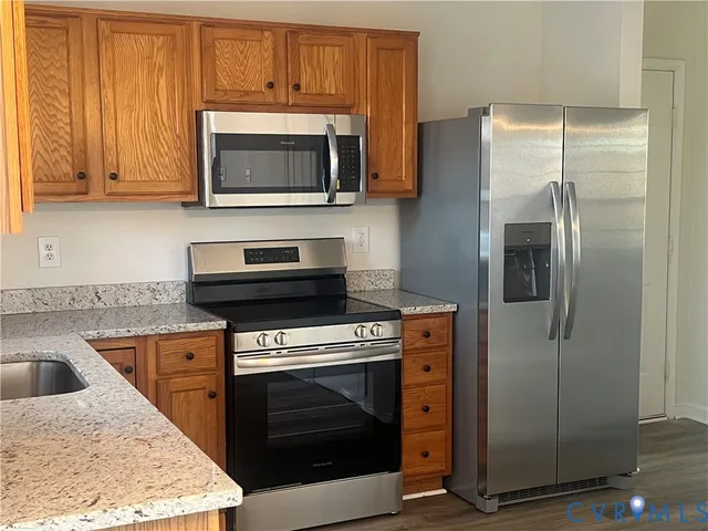 a kitchen with granite countertop a stove microwave and refrigerator