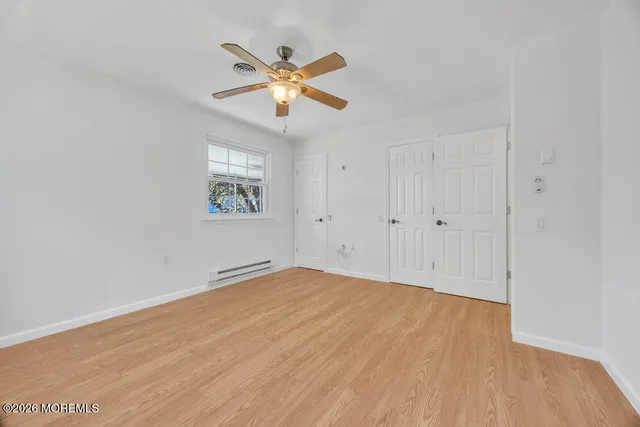 a view of an empty room with chandelier fan and wooden floor