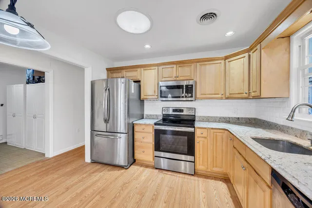 a kitchen with granite countertop a refrigerator stove and sink