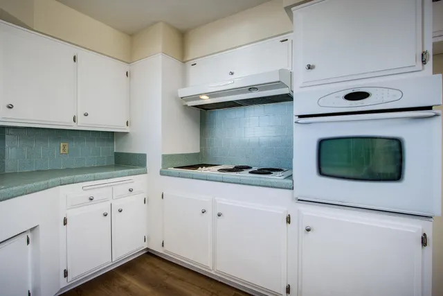 a kitchen with cabinets appliances and a wooden floor