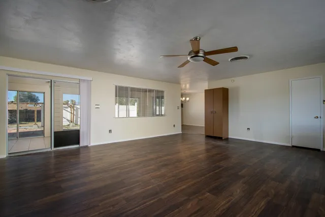 a view of an empty room with a window and wooden floor