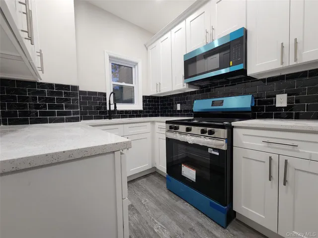 a kitchen with granite countertop a stove sink and microwave