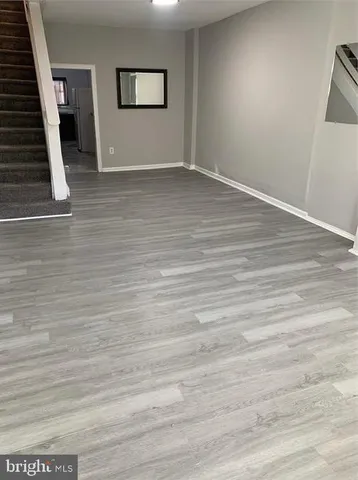 a view of an empty room with wooden floor and stairs