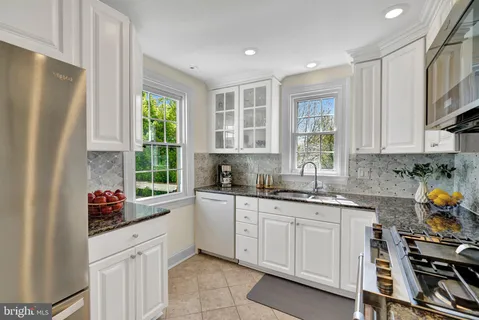 a kitchen with white cabinets and window