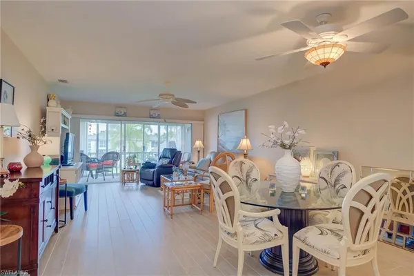 a view of a dining room with furniture a chandelier and large windows