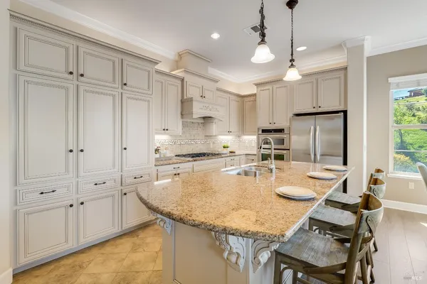 a kitchen with granite countertop stainless steel appliances a stove a sink and white cabinets