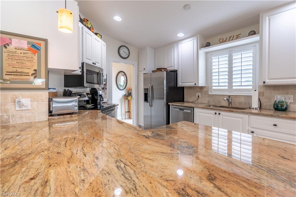 7568 Novara Court Naples, FL 34114 - Photo 12 of 34 a large kitchen with stainless steel appliances kitchen island granite countertop a refrigerator and a sink