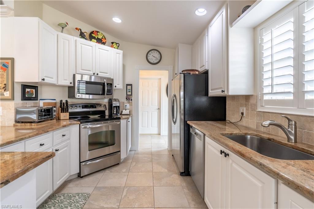 7568 Novara Court Naples, FL 34114 - Photo 13 of 34 a kitchen with stainless steel appliances granite countertop a sink a stove a refrigerator a microwave and cabinets