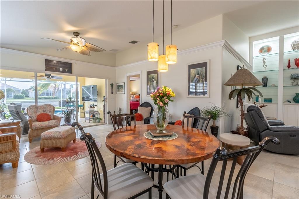 7568 Novara Court Naples, FL 34114 - Photo 17 of 34 a view of a dining room with furniture a chandelier and large windows