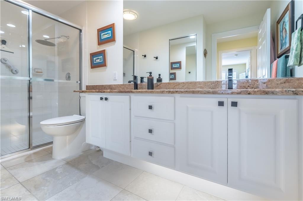 7568 Novara Court Naples, FL 34114 - Photo 24 of 34 a bathroom with a granite countertop sink mirror and toilet