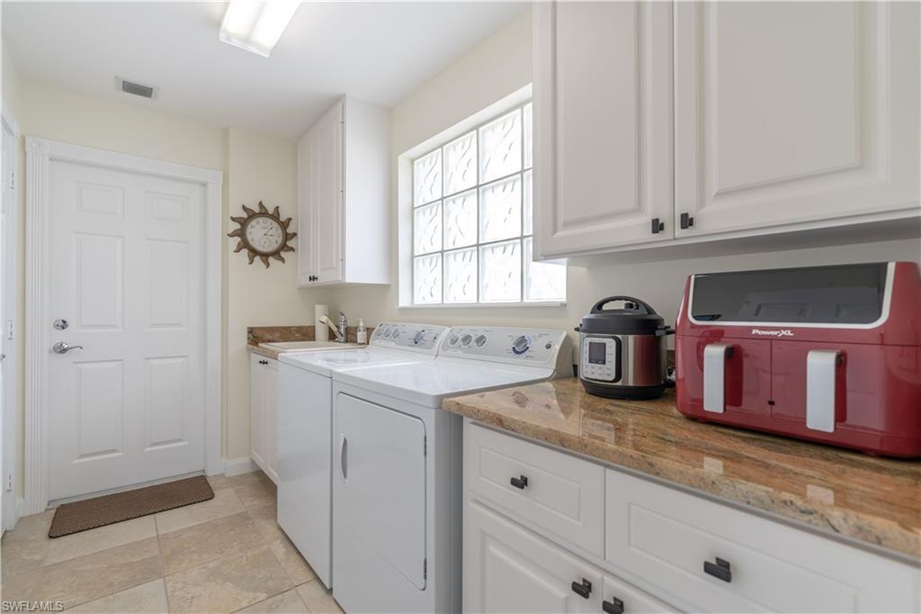 7568 Novara Court Naples, FL 34114 - Photo 25 of 34 a kitchen with granite countertop a sink and white cabinets