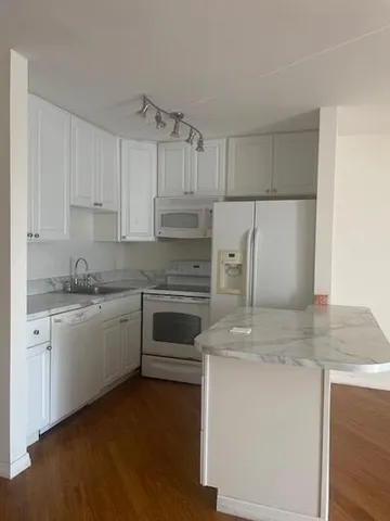a kitchen with granite countertop white cabinets and white stainless steel appliances