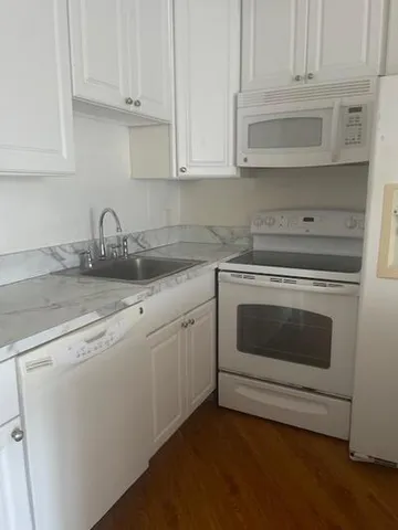 a kitchen with granite countertop white cabinets and stainless steel appliances