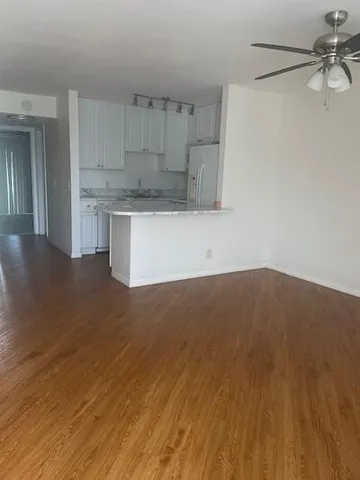 a view of a hallway with wooden floor and a kitchen