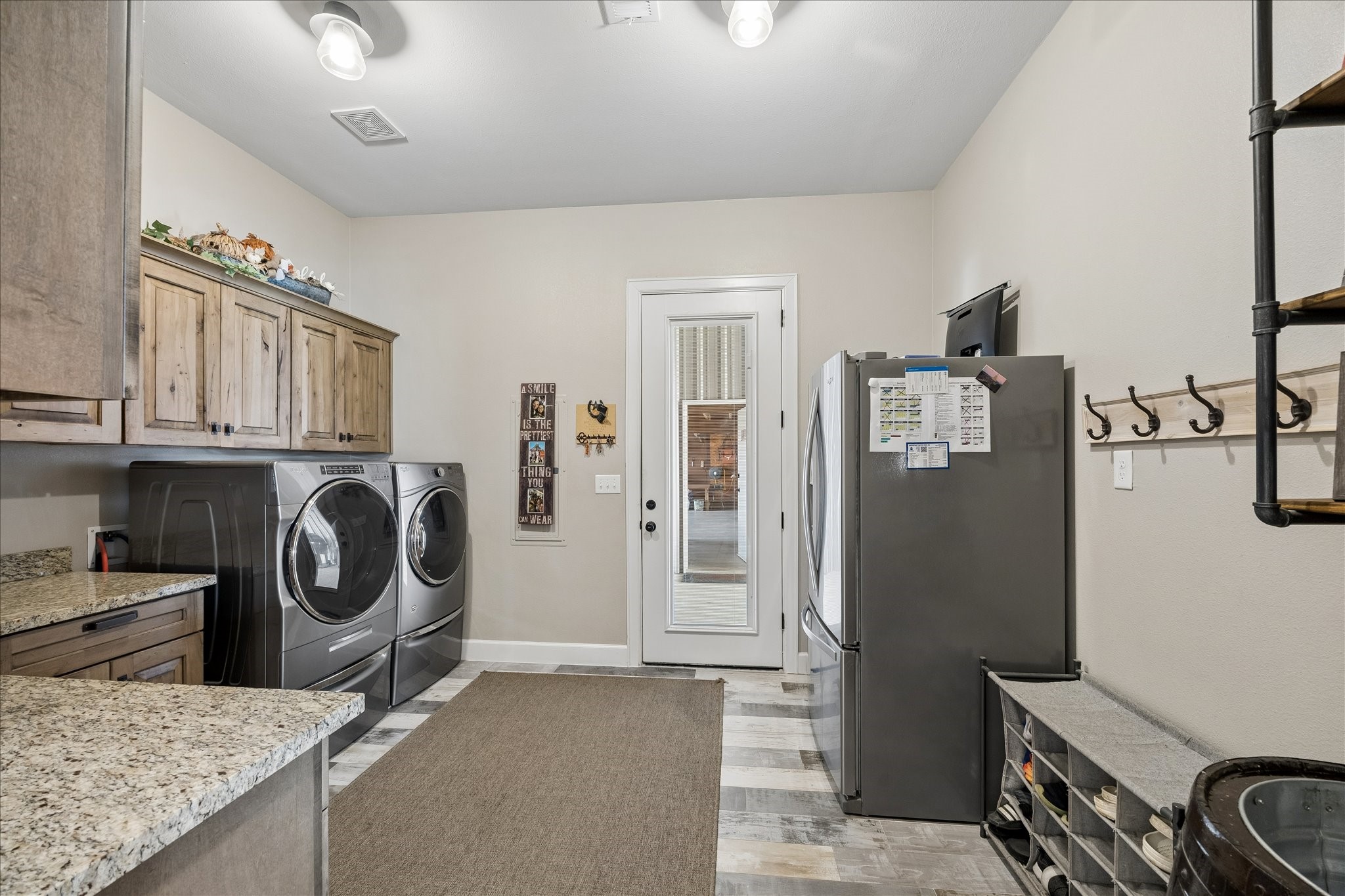 2224 Maler Road Sealy, TX 77474 - Photo 29 of 50 This spacious laundry room features ample counter space, and rustic wooden cabinets. It has lots of storage and a door leading outside.