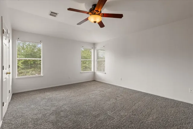 an empty room with windows and fan