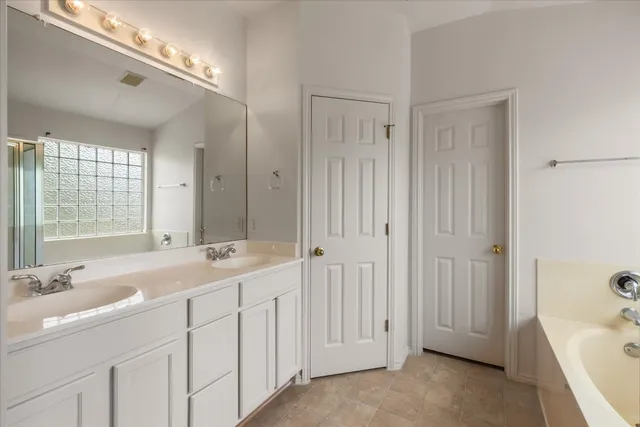 a spacious bathroom with a double vanity sink a mirror and a bathtub
