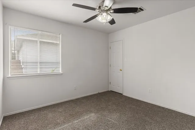 an empty room with a window and a fan