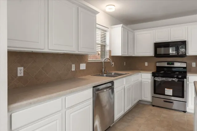 a kitchen with stainless steel appliances granite countertop a sink a stove and a microwave
