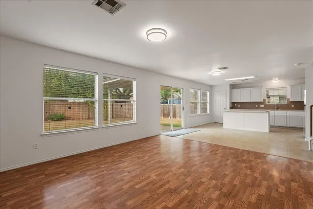 a view of an empty room with a window and wooden floor