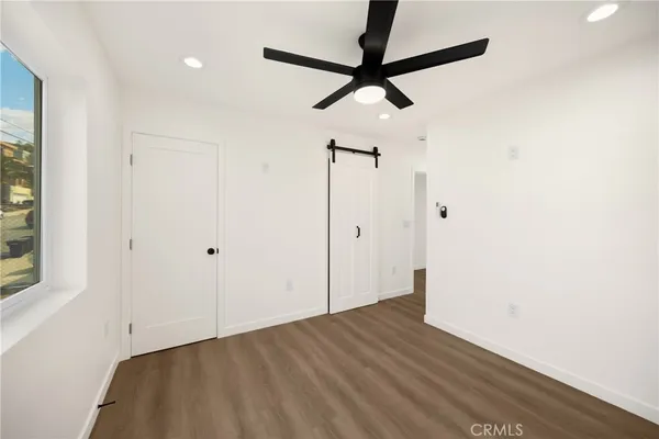 a view of empty room with wooden floor and fan