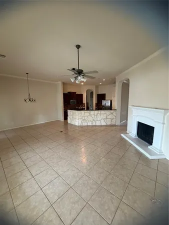 an empty room with wooden floor chandelier fan and windows