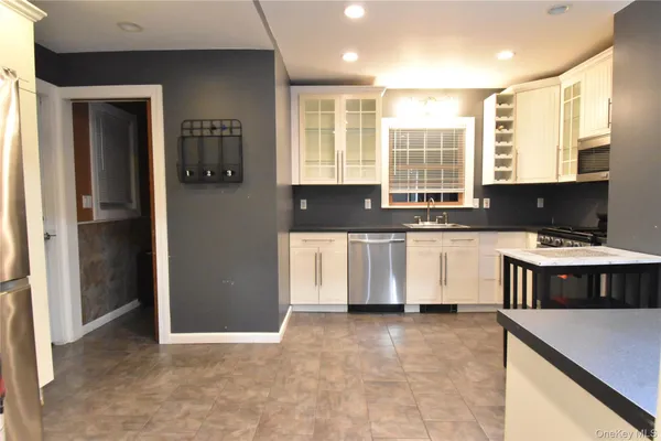 a large kitchen with stainless steel appliances granite countertop a sink a stove and a refrigerator