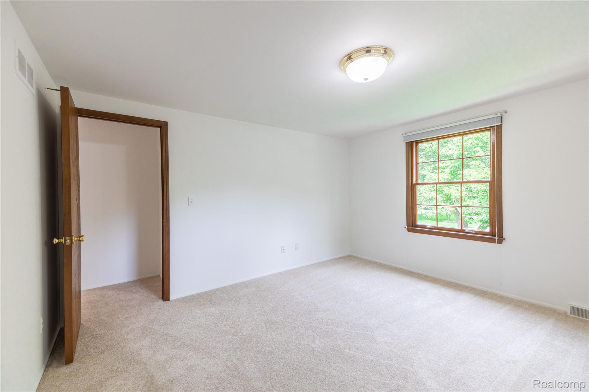 7611 Ferry Road Grosse Ile, MI 48138 - Photo 39 of 51 Neutral wall finishes with a window featuring wood trim, a light-filtering shade, and a green outdoor scenery