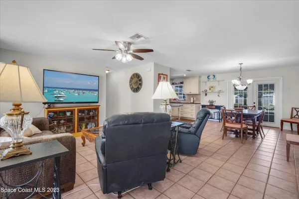 a living room with furniture a chandelier and a flat screen tv