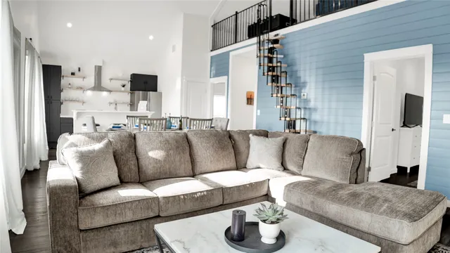 a living room with furniture kitchen view and a wooden floor