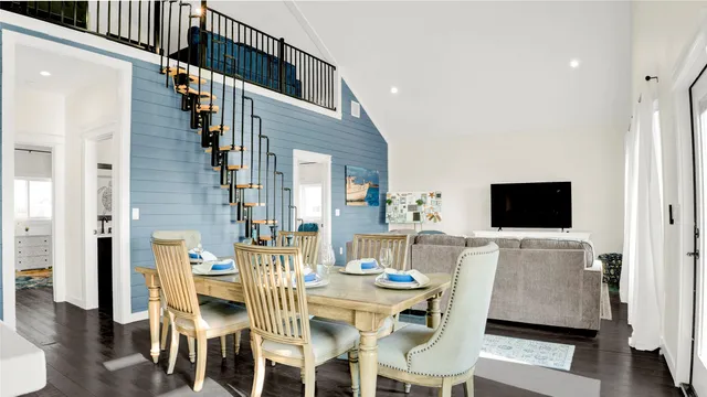 a kitchen with stainless steel appliances kitchen island a table chairs in it and wooden floor