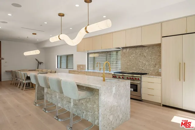 a kitchen with kitchen island a stove a chandelier a sink a dining table and chairs