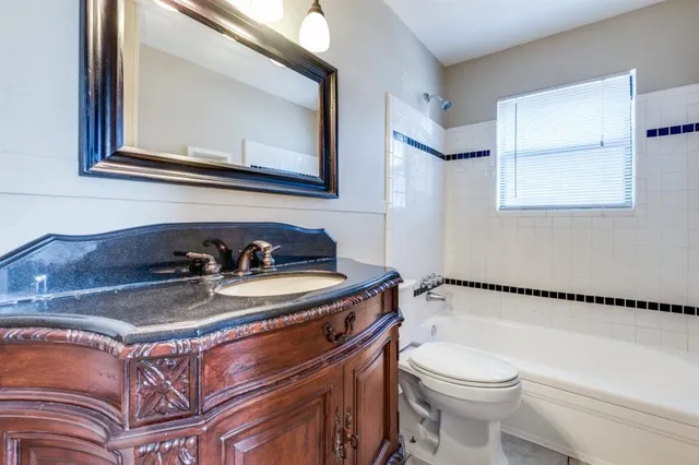 a bathroom with a granite countertop toilet sink and mirror