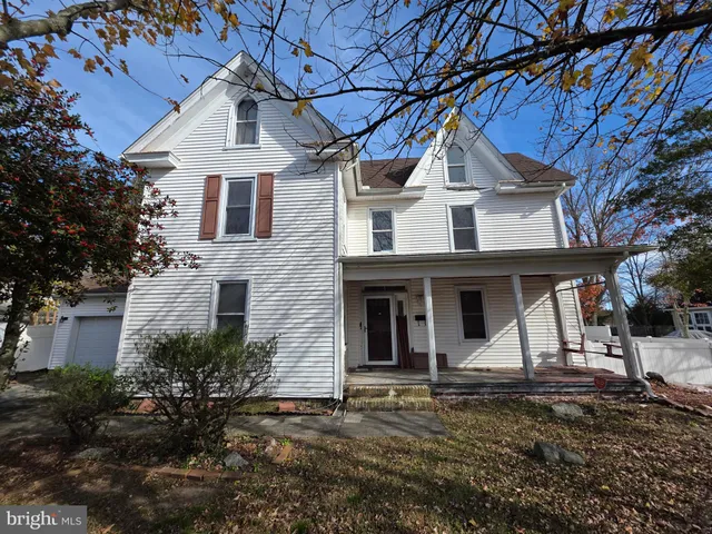 a view of a white house with a large tree and windows