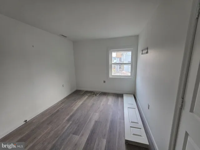 an empty room with wooden floor and window