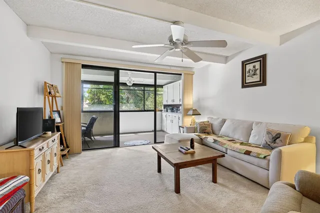a living room with furniture a flat screen tv and a floor to ceiling window