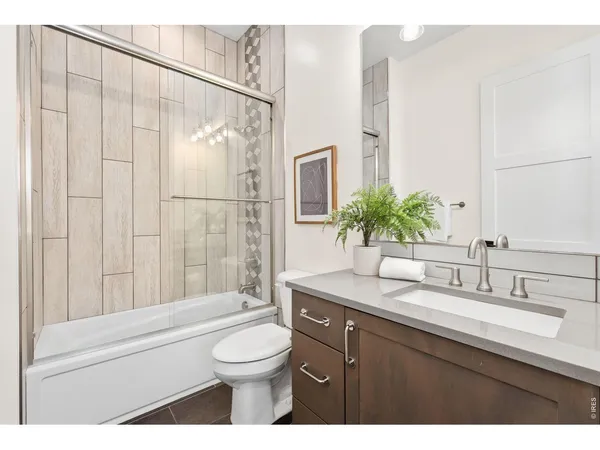 a bathroom with a granite countertop sink a toilet a mirror and shower