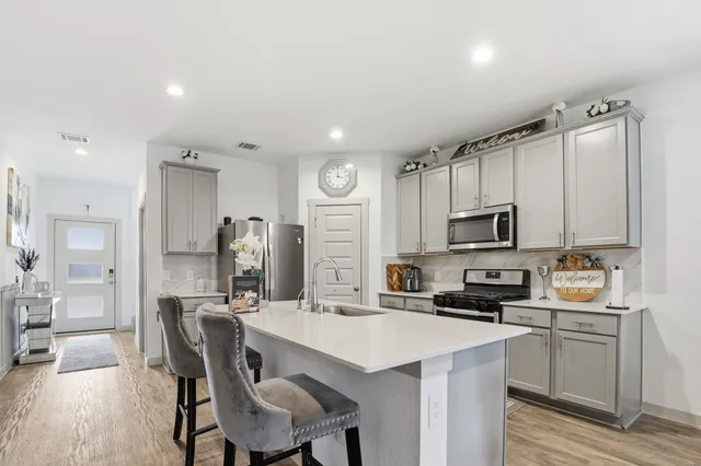 a kitchen with stainless steel appliances a stove top oven a sink refrigerator and cabinets