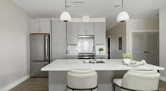 a kitchen with stainless steel appliances a dining table chairs and a refrigerator