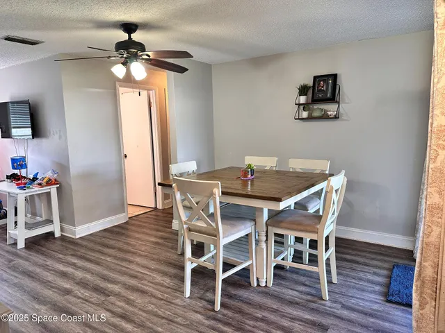 a dining room with wooden floor a chandelier a wooden table and chairs